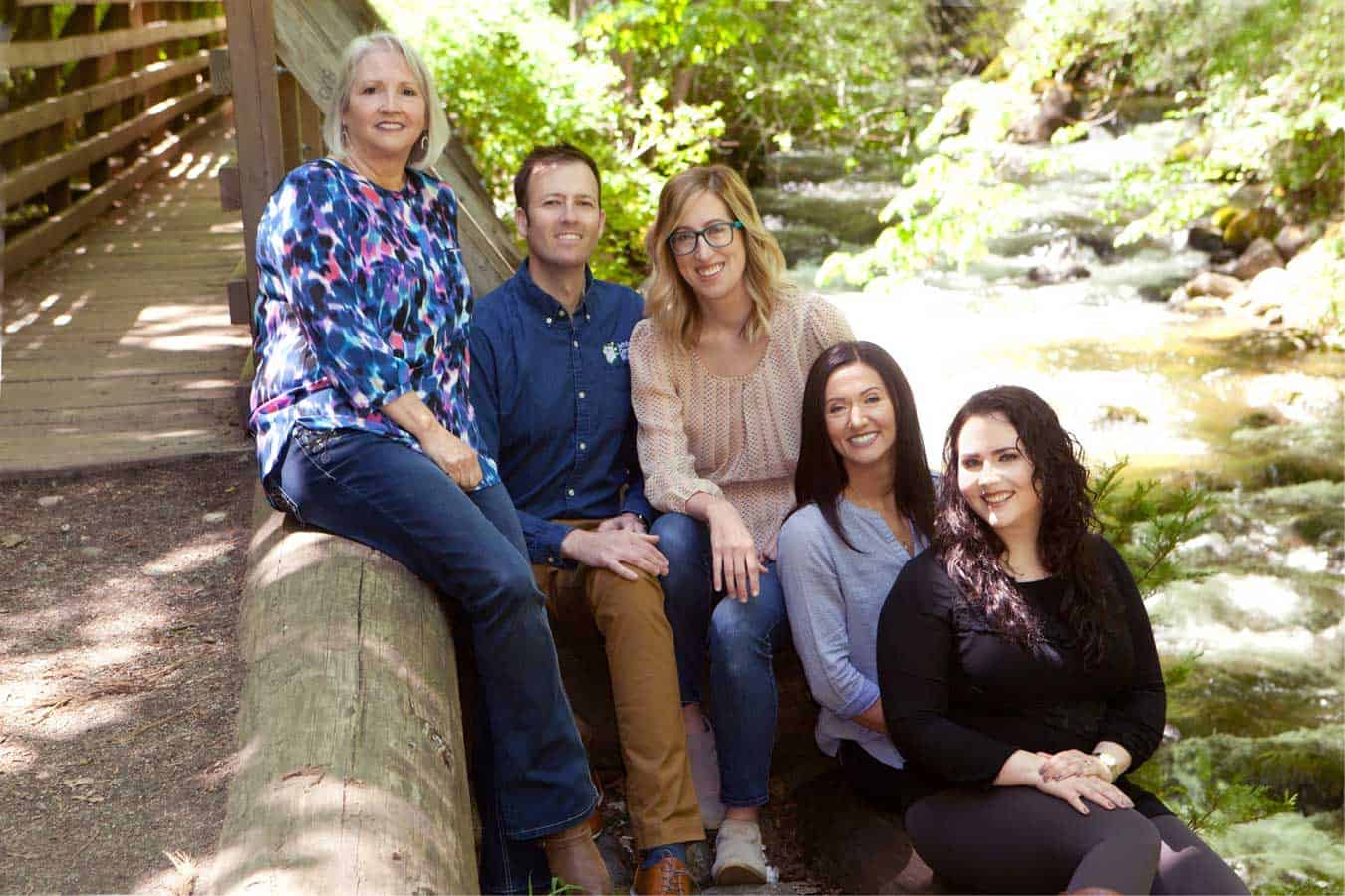 Dr. White surrounded by his staff sitting next to Lithia Park's Ashland Creek in Ashland, OR